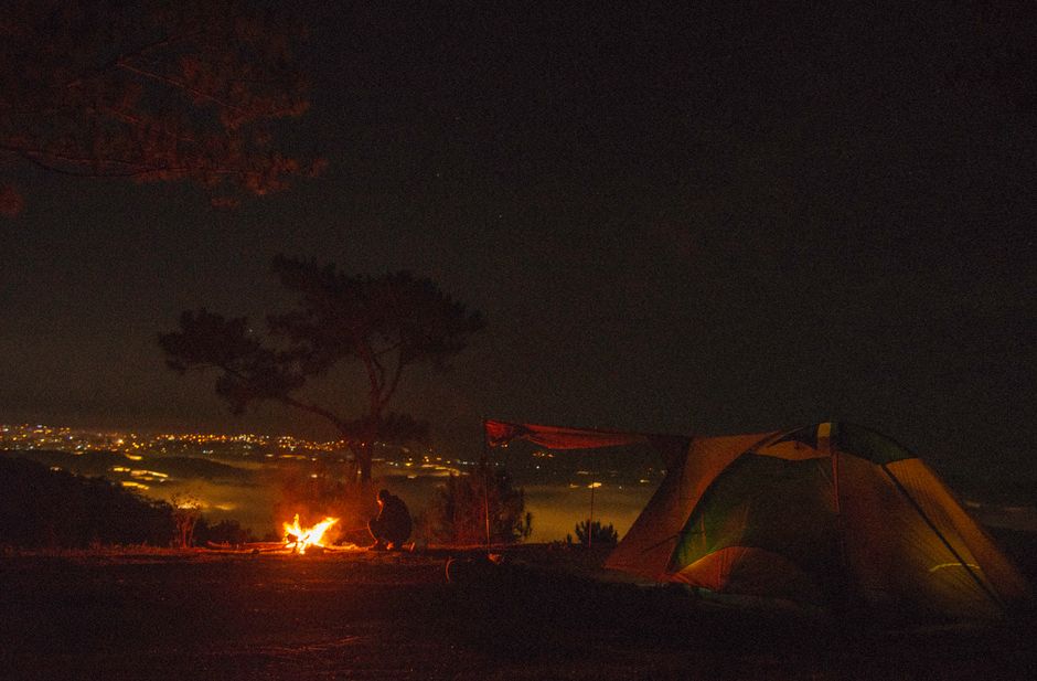 A serene camping scene with a tent and campfire under the night sky. Perfect solitude.