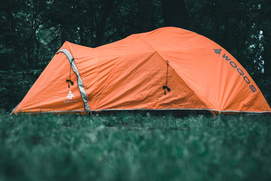Bright orange tent in a Canadian forest, ideal camping scene.